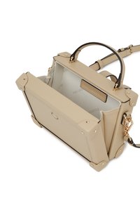 Beige bőr kézitáska arany hardware-rel, strukturált forma, kontrasztos fekete kiegészítőkkel és elöl nyíló felhajtóval. A belsejében a márkajelzés mintázata látható.