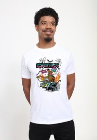 Bílé bavlněné tričko s barevným motivem Scooby-Doo v závodním voze, plameny, duchové a netopýři. Kulatý výstřih, krátké rukávy.