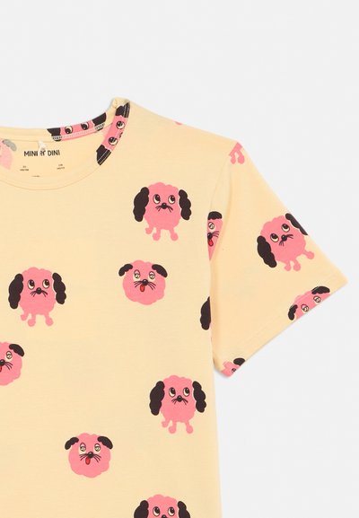 Geel shirt met korte mouwen bedrukt met herhalende roze hondenkoppen met zwarte oren en expressieve ogen over de stof.