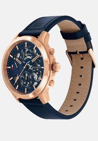 Montre chronographe avec un bracelet en cuir bleu marine, un boîtier en acier inoxydable avec finition en or rose, un cadran bleu et un affichage de la date. Comprend plusieurs sous-cadrans.