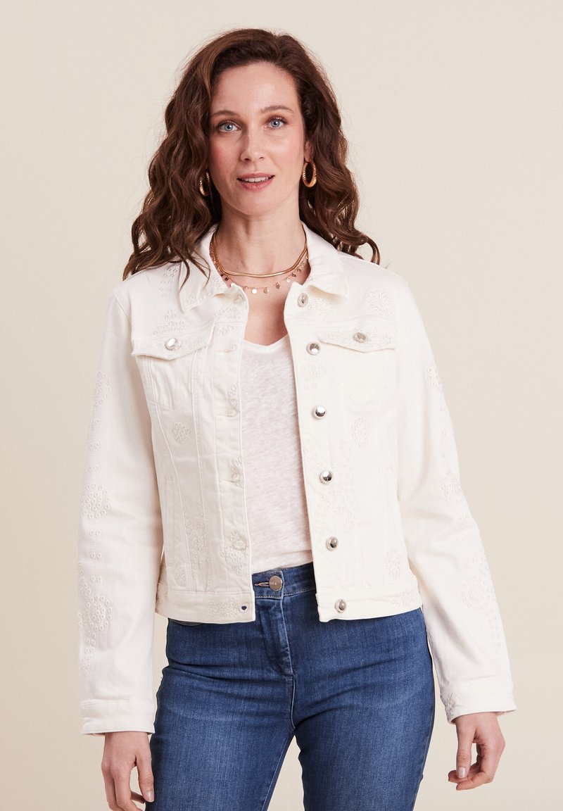 Witte denim jas met reliëf bloemenpatronen, zilveren knopen en klassieke kraag. Gemaakt in combinatie met een licht topje en blauwe jeans.
