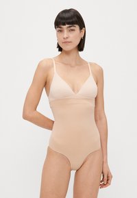 Nuoga bodysuit su V formos iškirpte, reguliuojamomis petnešomis, minkšta tekstūra ir be siūlių konstrukcija, užtikrinanti sklandų prigludimą.