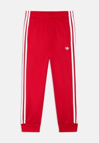 Κόκκινο παντελόνι φόρμας με λευκές πλαϊνές ρίγες, ελαστική μέση και ριμπ μανσέτες. Το υλικό φαίνεται λείο με κεντημένο λογότυπο.