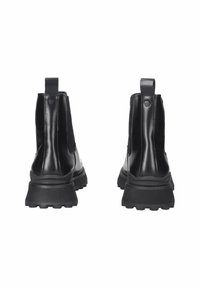 Stivaletti neri alla caviglia con una parte superiore lucida e slanciata, pannelli laterali elasticizzati e una suola in gomma spessa e strutturata con un'etichetta al retro.