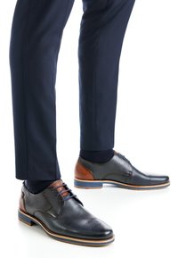 Musta nahkainen juhlakenkä, jossa on teksturoidun pinnan ja ruskeat yksityiskohdat, nauhat ja kontrastinen sininen viimeistely pohjassa.