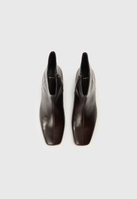 Καφέ δερμάτινα μποτάκια αστραγάλου με ομαλή επιφάνεια, τετράγωνη μύτη και κάθετους φερμουάρ. Ο σχεδιασμός διαθέτει εκλεπτυσμένη γραμμή.