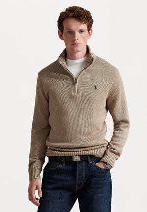 Maglione beige con zip e collo alto realizzato in tessuto a maglia testurizzata, dotato di un orlo a coste, colletto a contrasto e piccolo logo verde sul petto.