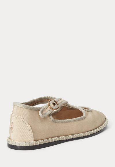 Μπεζ παπούτσι Mary Jane με επίπεδη σόλα, πάνω μέρος από ύφασμα, διακοσμητικό λουρί με αγκράφα, ραμμένο περίγραμμα και μαύρη σόλα, σε πλευρική όψη.