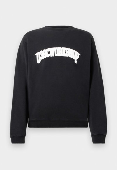 Sort langærmet sweatshirts med hvid tekst i fede bogstaver "OBSC WORKSHOP" buet over brystet, rund halsudskæring og ribbede manchetter og kant.