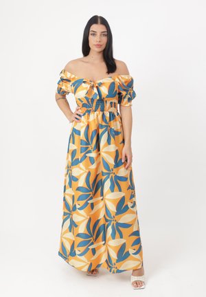 Robe maxi décolletée en jaune vif avec des motifs floraux bleus et blancs. Pr�ésente une taille smockée et des manches bouffantes froncées.