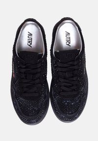 Sneaker in suede nera con superficie testurizzata, che presenta lacci neri e un logo sobrio sulla linguetta. Accenti metallici sui lati.
