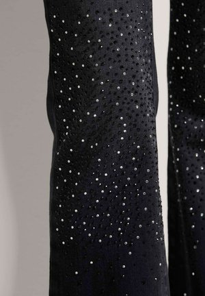 Zwarte stof met een textuur, versierd met verspreide zwarte en zilveren strassstenen die een gradiënt-effect over het oppervlak creëren.