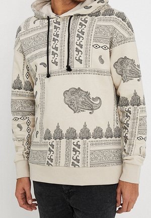 Felpa con cappuccio beige caratterizzata da intricati motivi neri, tra cui disegni paisley e floreali, con cappuccio regolabile e tasca a marsupio frontale.