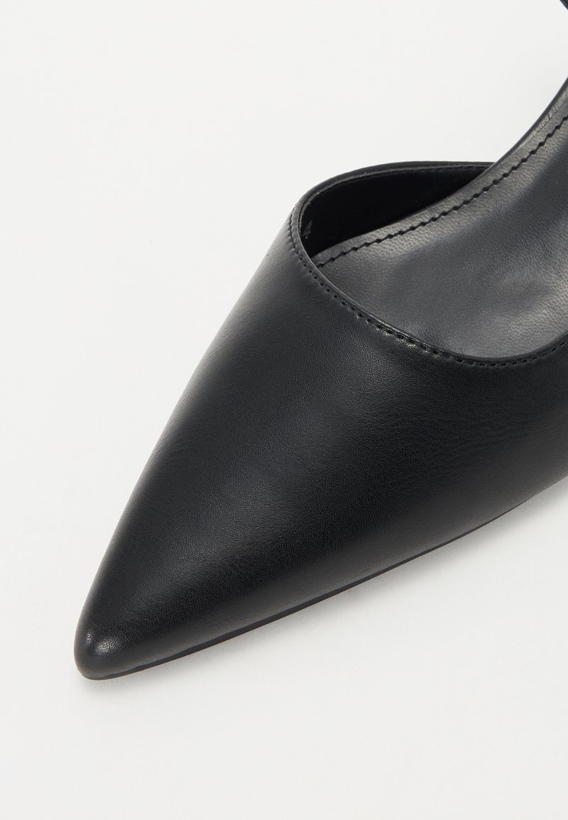 Scarpa nera in pelle con punta affusolata, dal profilo basso e dalla texture liscia. Presenta un design elegante e dettagli di cucitura minimalista.