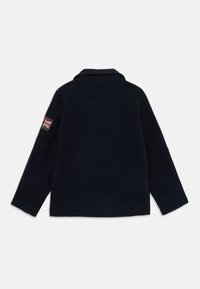Navy blue flis jakna z ovratnikom, dolgimi rokavi in pravokotno nalepko z britansko zastavo na levem rokavu.