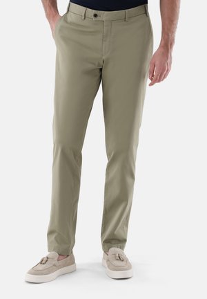 Beige Chinos mit schmaler Passform, ausgestattet mit einer glatten Textur und Fronttaschen, kombiniert mit hellen Slippers.