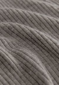 Šedá žebrovaná pletenina zobrazuje měkkou texturu s jemným leskem, charakterizovaná výraznými vertikálními liniemi a mírnými variacemi ve vazbě.