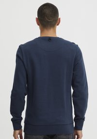 Marineblå bomullsgenser med lange ermer, ribbede mansjetter og rund hals, med en løkkedetalj bak.