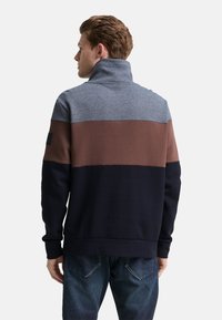 Sweatshirt mit Farbblockdesign in Blau, Braun und Marine. Hoher Kragen, gerippte Bündchen und weiche Strickstruktur, sichtbar von hinten.