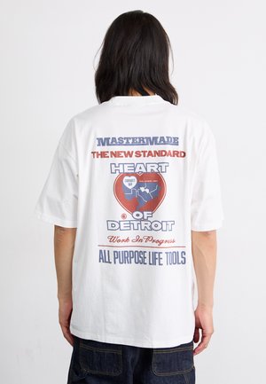 T-shirt in cotone bianco con una grande grafica sul retro, con testo rosso e blu e una forma di cuore che enfatizza "Heart of Detroit".