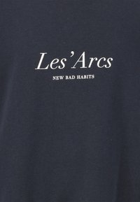 Mörkblå bomulls t-shirt med texten "Les'Arcs" och "NEW BAD HABITS" i vit serif-typsnitt, med en mjuk yta och avspänd passform.