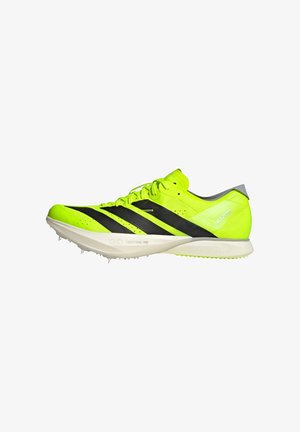 Aikuisten juoksukenkä, jossa kirkkaan neonkeltaiset päälliset, mustat raidat, teksturoitu verkkokangas ja valkoinen pohja, jossa on pitoon tarkoitetut piikit.