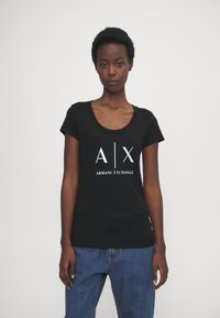 Čierne tričko s krátkym rukávom a okrúhlym výstrihom. Obsahuje biele logo "A|X ARMANI EXCHANGE" na prednej strane. Mäkký bavlnený materiál.