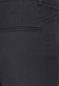 Pantaloni navy realizzati in tessuto testurizzato, caratterizzati da un motivo a costina diagonale, una tasca posteriore e un design a taglio slim.