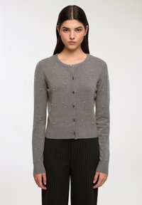 Cardigan lavorato a maglia grigio con scollo rotondo, chiusura frontale con bottoni e dettagli in perle sparse. Maniche lunghe e orlo a coste.