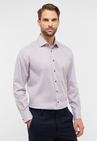 Camicia a bottoni di colore lilla chiaro con piccole macchie blu navy, maniche lunghe e colletto. Presenta bottoni marroni e una tasca sul petto.