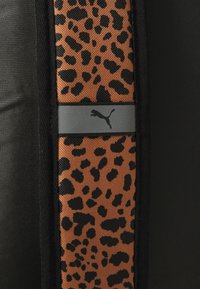 Crna sportska tkanina s panelom u smeđe-crnom leopardskom uzorku, uz sivu horizontalnu prugu na kojoj je prikazan Puma logo.