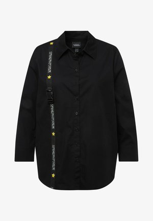 Sort skjorte med lange ærmer, har en kontrasterende justerbar rem med gule stjernet detaljer over skulderen. Glat stofstruktur.