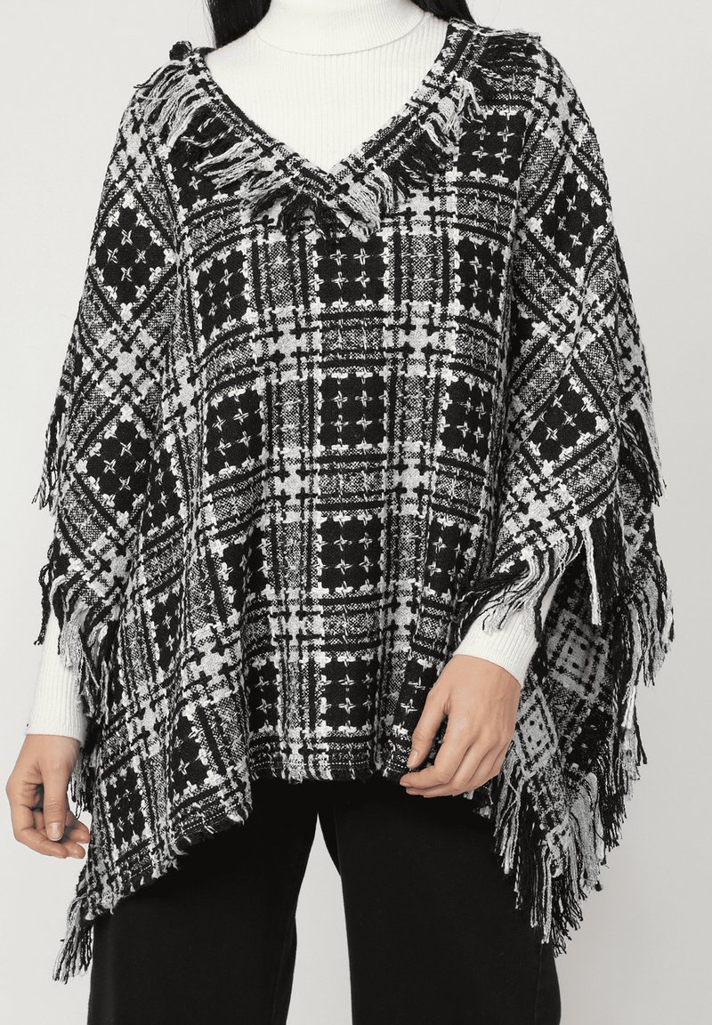 Poncho a cuadros en blanco y negro con dobladillo con flecos, hecho de un tejido texturizado; presenta un escote en V y un diseño de corte holgado.