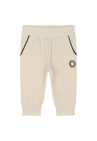 Joggers in velluto a coste nocciola chiaro con cuciture blu, due tasche laterali e una piccola etichetta in pelle marrone sul fronte. Tessuto morbido, vita elasticizzata.