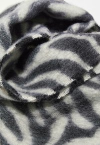 Écharpe en laine avec un motif rayé animal en noir et crème, dotée d'une texture douce et de coutures visibles le long des bords.