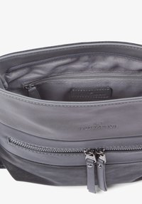 Sac en cuir gris avec plusieurs compartiments zippés, présentant une texture lisse et des coutures discrètes. Logo embossé à l'intérieur.