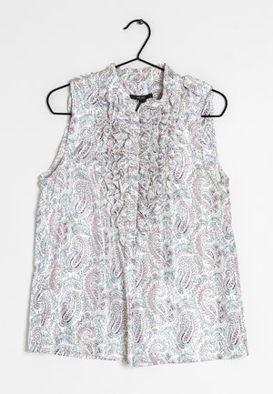 Ærmeløs hvid bluse med pink og blå paisleymønster, flæsedetalje foran, hængende på sort bøjle mod hvid baggrund.