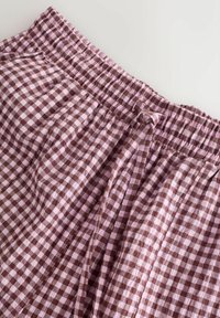 Pantaloni scurți cu model gingham maro și roz, cu talie elastică și șnur. Materialul pare ușor, cu o suprafață texturată.