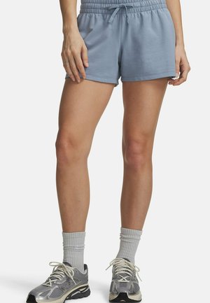 Persoon die lichtblauwe shorts met elastische taille, grijze crewkousen en grijze hardloopschoenen draagt, staand tegen een witte achtergrond.