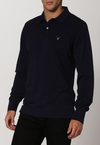 Navyfarbener Langarm-Polohemd aus Baumwolle, mit Kragen, Knopfverschluss und kleinem Logodetail auf der Brust.