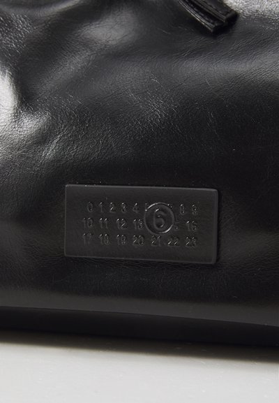 Black leather surface with a rectangular tag displaying embossed numbers 0-23, with number 6 circled in the center.