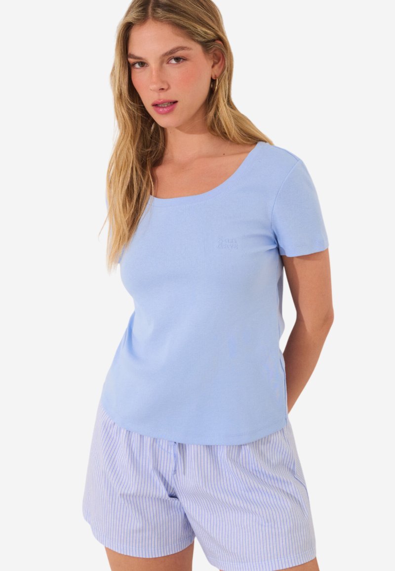 Ljusblå kortärmad t-shirt med rundad halsringning, tillverkad av mjukt material, tillsammans med randiga pyjamasbyxor i blått och vitt.