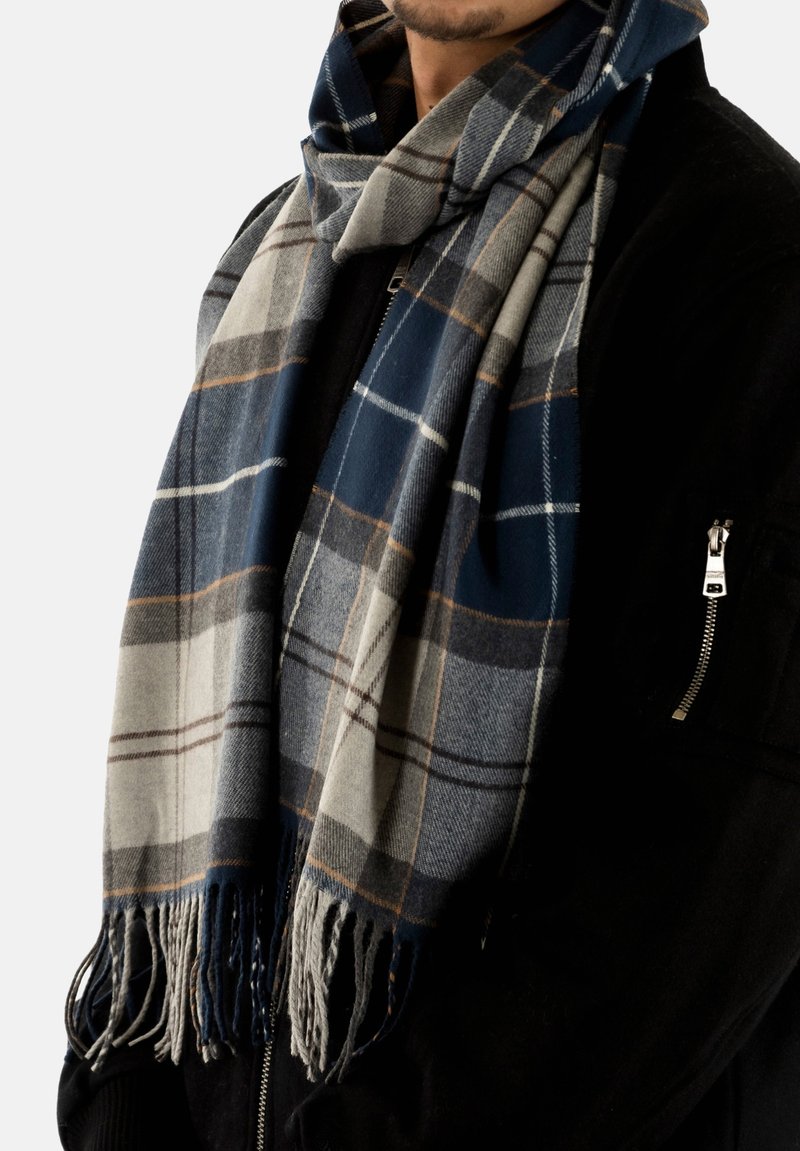 Wollen sjaal in marineblauw, grijs en crème met een ruitpatroon. Heeft franjes aan de randen en een zachte textuur die om de nek hangt.