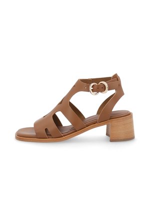 Sandalia de cuero marrón con diseño calado, correa ajustable con hebilla y tacón bajo de madera.