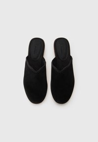 Sorte semskede slip-on sko med rund tå og en teksturert, bølget kant. Innvendig har de en merket innersåle med en myk overflate.
