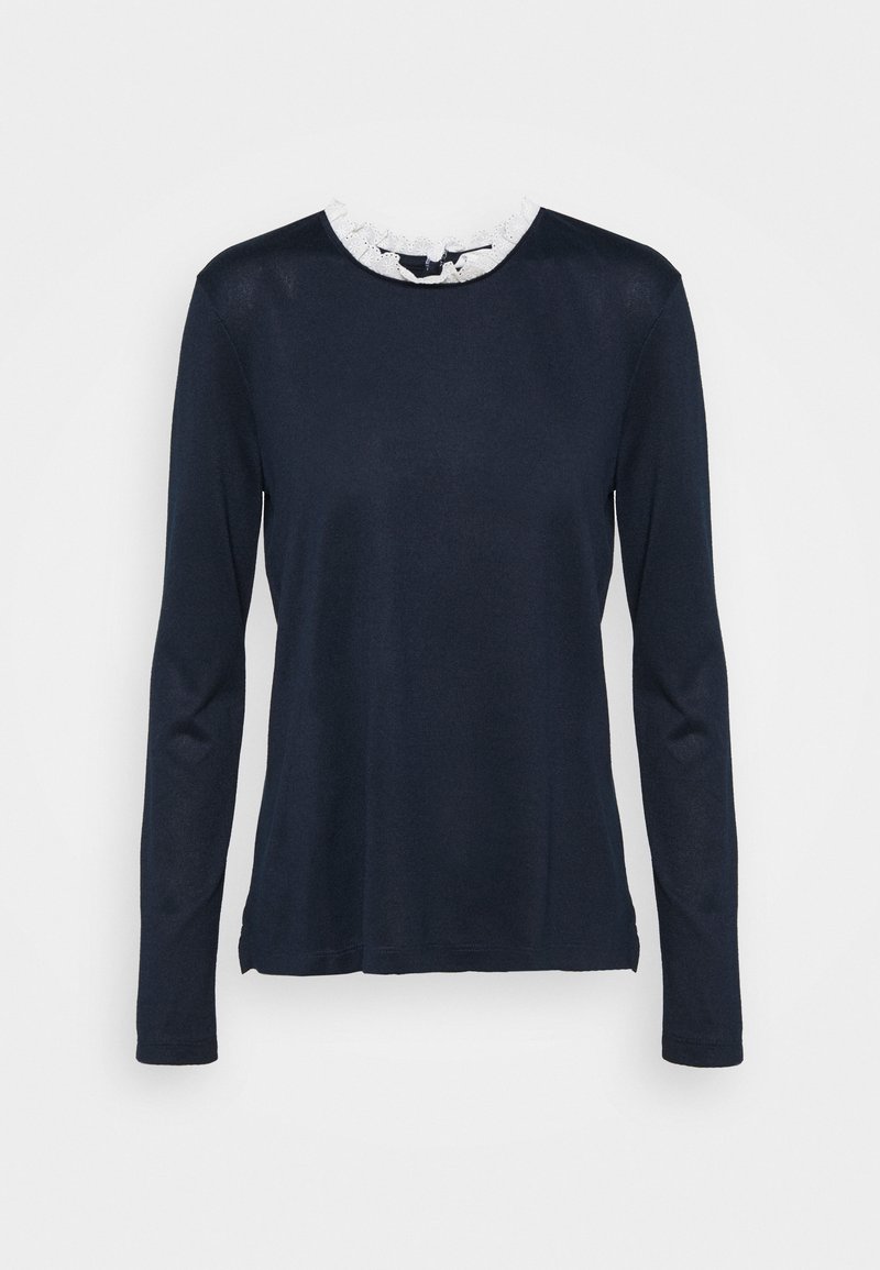 Haut à manches longues bleu marine avec détail de col à volants en dentelle blanche et fermeture par bouton à œillet dans le dos.