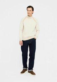 Kreemikas kootud kampsun soonikkoega krae ja varrukaotstega, kombineeritud tumelõheliste teksade ja pruunide tennistega. Lihtne ja moodne lõige.