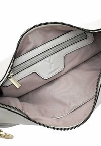 Interno di borsa in pelle bianca con una texture liscia, tasca con zip e hardware color oro, con fodera grigia chiara.