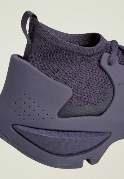 Close-up of a purple sock-style sneaker with textured knit upper and thick rubber sole featuring ventilation holes.