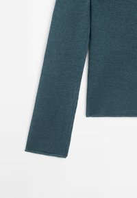 Teal knitted sweater showing a long sleeve and straight-cut hem, featuring a smooth texture and even stitching along the edges.